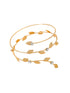 Gold bracelet with leaf designs and small stones on a beige fabric background
