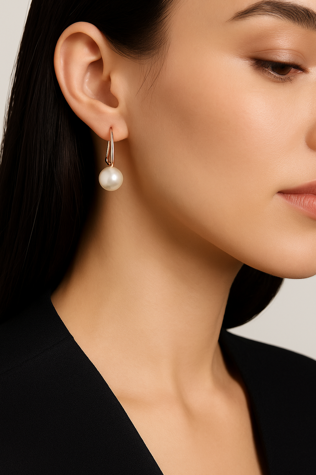 Close-up of a person wearing pearl earrings with a neutral background