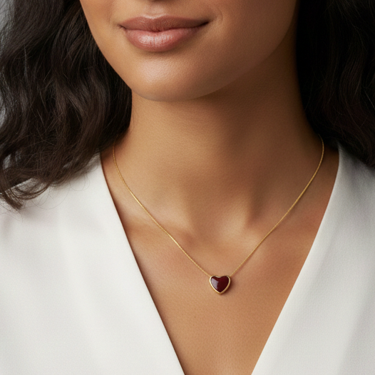 Woman wearing a white blazer and gold necklace with a heart pendant on a gray background