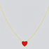 Gold necklace with a red heart pendant on a light gray background